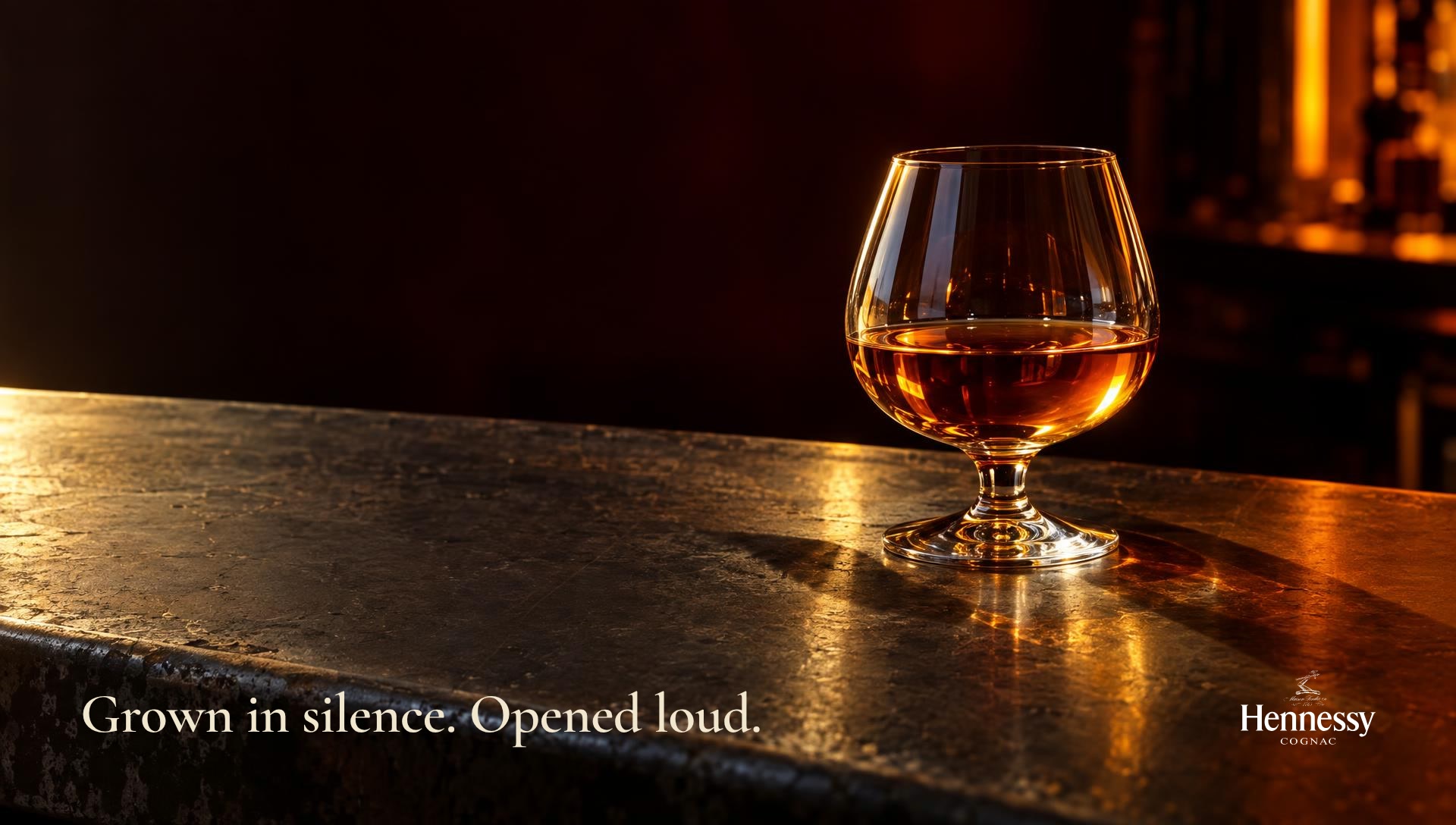 A tasting glass lit warm on a zinc bar